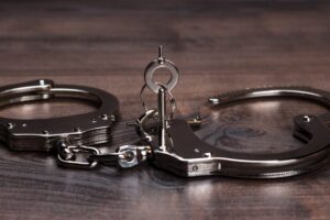 Handcuffs and a key on a table, representing counterfeit crime charges explained by a Newport Beach criminal defense attorney.