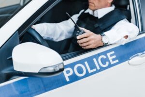 Police officer inside a patrol car during a traffic stop, illustrating situations explained by a San Diego criminal defense attorney.