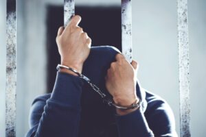 Man standing behind jail bars representing the California bail process explained by an El Cajon Criminal Defense Attorney.