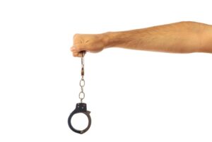 Police officer holding arrest handcuffs representing the steps to take after learning of an arrest warrant with guidance from a San Diego Criminal Defense Attorney.